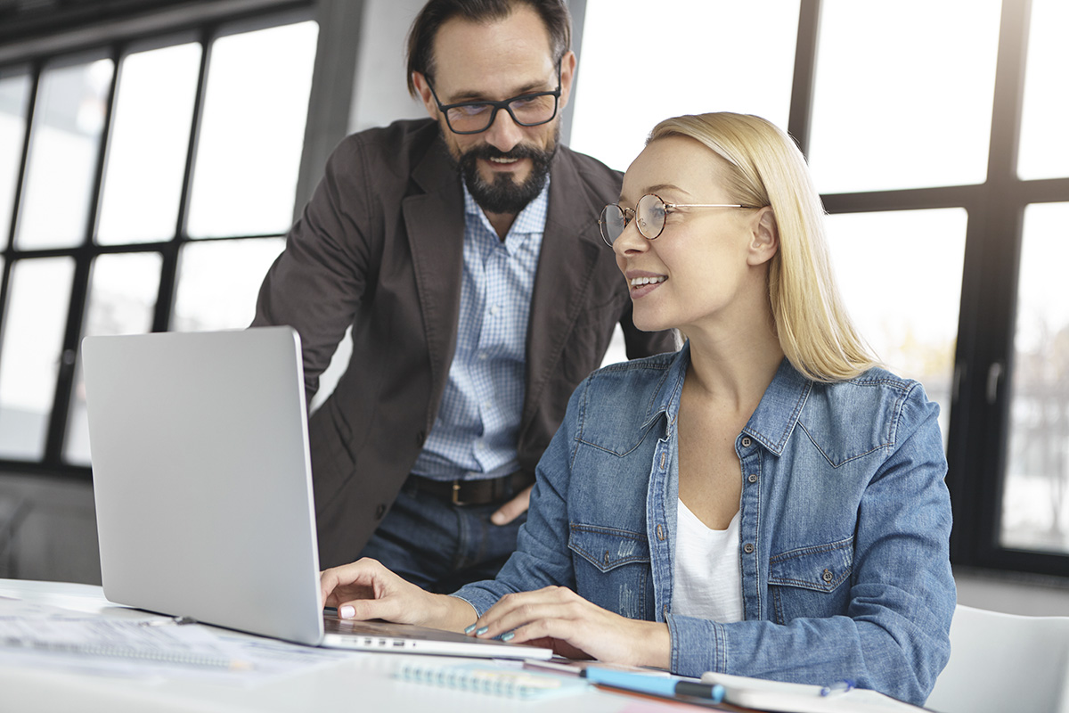 Mann-schaut-Frau-bei-der-Arbeit-über-die-Schulter-und-kommuniziert